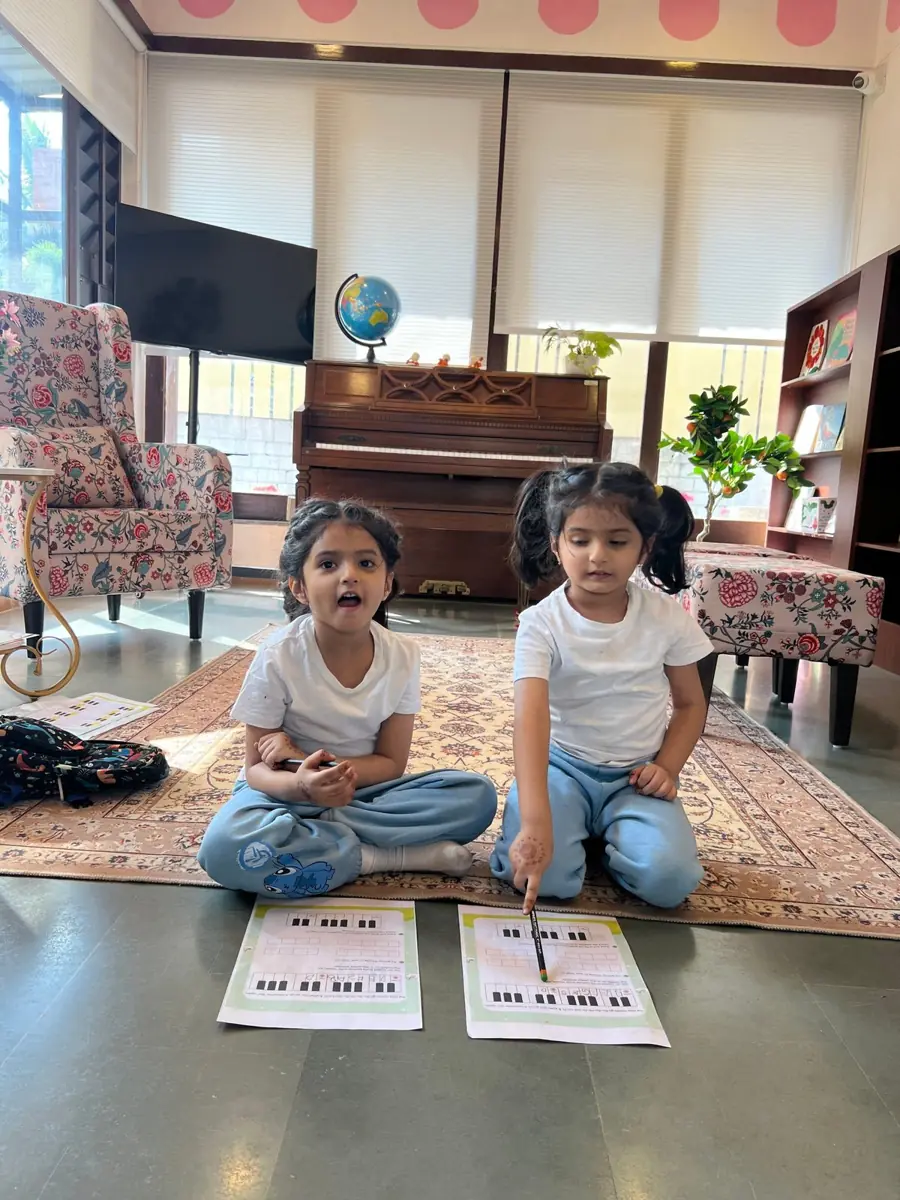 Two girls learning piano keys at circle time