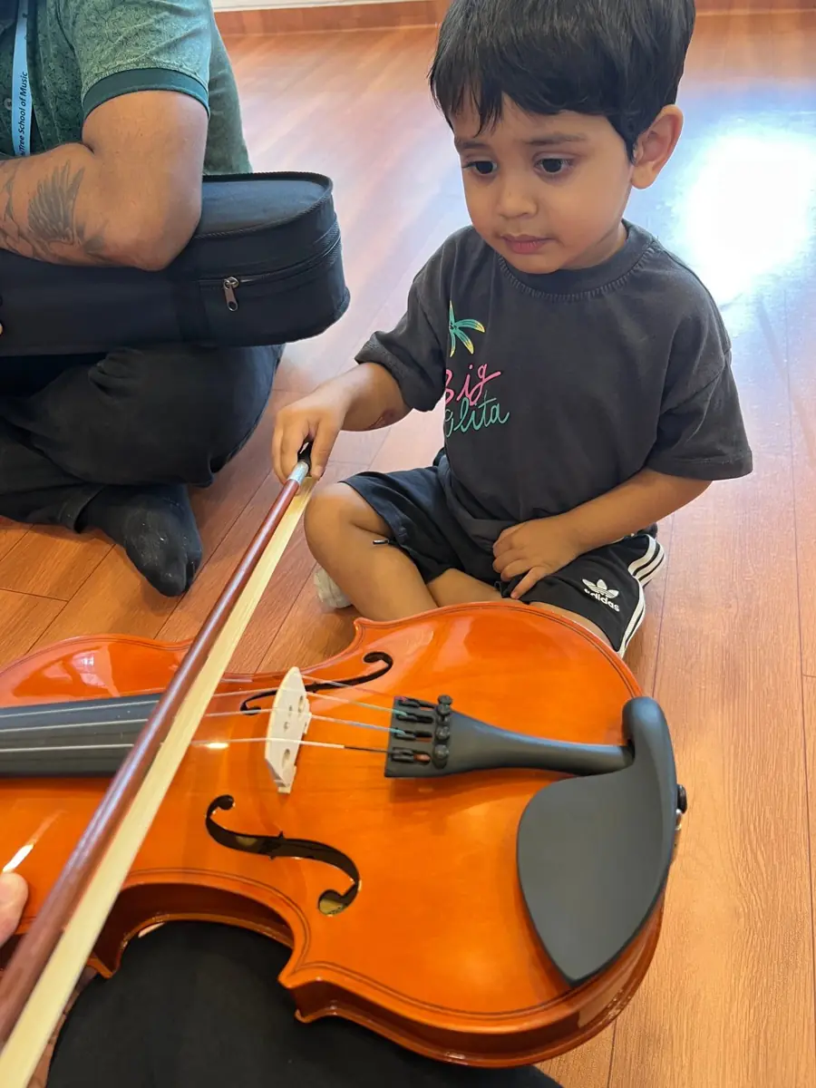 A toddler meets the violin during music time