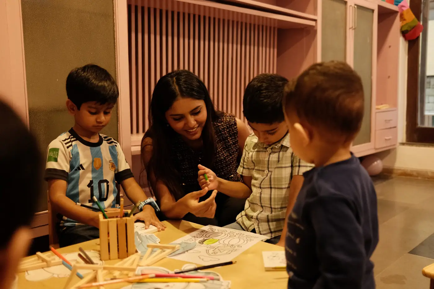 A teacher colouring with children at the art table